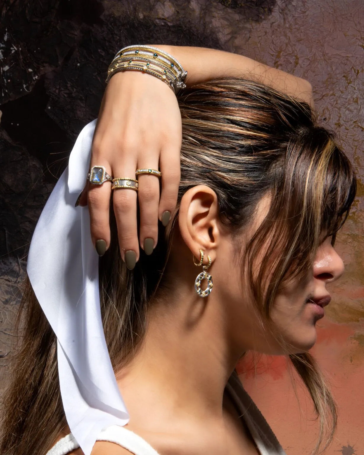 model with her hand above her head with bangles with rings on her hand and arm