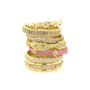 stack of gold rings with one pink colored ring