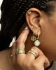 woman pointing to ear of earrings with her fingers having rings