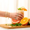 grabbing a drink with fruit surrounding a jewelry on the models hand