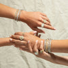 models wearing bangles and rings on hands touching each other